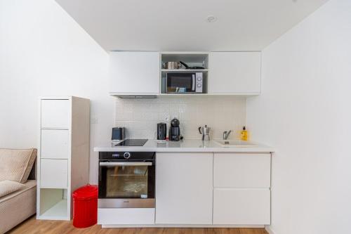 - une cuisine avec des placards blancs et un canapé dans l'établissement GuestReady - A Downtown stay in Bordeaux, à Bordeaux