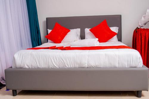 a bed with red and white pillows on it at The Loch Hotel Bondo in Bondo