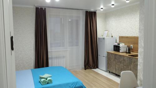 a room with a bed and a kitchen with a refrigerator at Новая 1 комнатная квартира в мкр Аэропорт in Kostanay