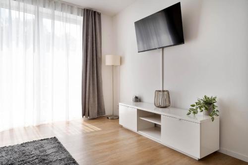 a white living room with a tv on a wall at Apartments in the city center I private parking I home2share in Dortmund