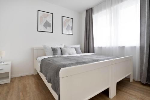 a white bedroom with a white bed and a window at Apartments in the city center I private parking I home2share in Dortmund