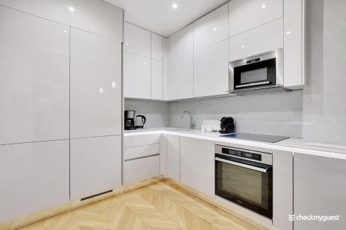 - une cuisine blanche avec des placards blancs et une cuisinière dans l'établissement Luxury apartment 4pers George V, à Paris