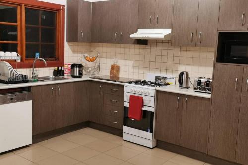 a kitchen with a stove top oven next to a sink at Kathmandu Farmstay - Pool Table, Ping Pong, Bicycles, PlayStation, Netflix, close to Bathurst and Mayfield Garden in Brewongle
