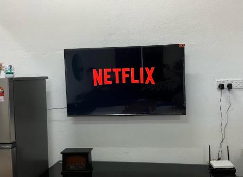 einen Fernseher mit dem Netflix-Schild an der Wand in der Unterkunft La Wood Homestay near Kuala Besut Jetty in Kampung Kuala Besut