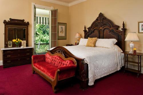 a bedroom with a large bed and a red chair at Devereaux Shields House in Natchez