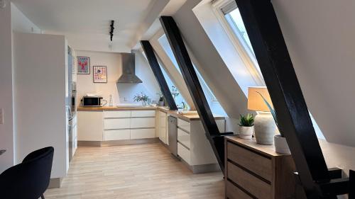 an attic kitchen with white cabinets and windows at Løvstræde apartments from 1 to 6 in Copenhagen