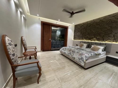 a bedroom with a bed and a chair at Ganga Euphoria - A Luxury Villa on the Ganges in Rishīkesh
