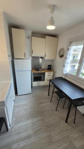 une cuisine avec une table et un réfrigérateur blanc dans l'établissement La Perle des Océans - Résidence Tobago!, à Canet