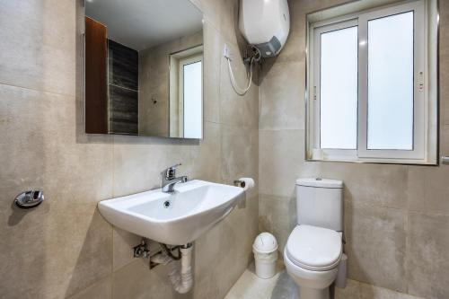 een badkamer met een wastafel, een toilet en een spiegel bij Dorris's Apartment 5 min walk from St Julians in San Ġwann