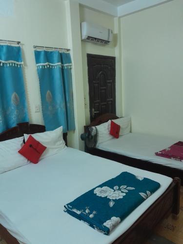 two beds in a room with blue curtains at NHÀ NGHỈ TRÀ MY NAM ĐỊNh in Vu Bản