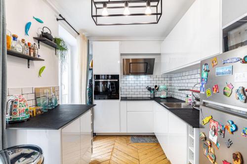 une cuisine avec des armoires blanches et des comptoirs noirs dans l'établissement GuestReady - Homely Dwelling near Canal St Martin, à Paris