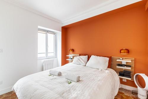 une chambre avec un grand lit avec un mur orange dans l'établissement GuestReady - Homely Dwelling near Canal St Martin, à Paris