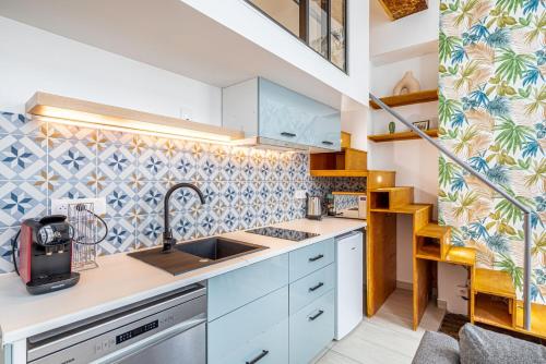 une cuisine avec des placards blancs et du carrelage bleu dans l'établissement GuestReady - Warm Getaway in Le Marais, à Paris