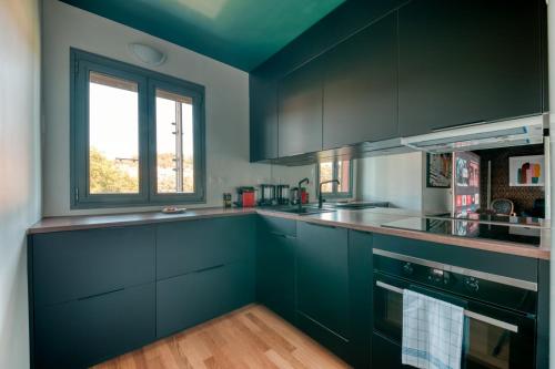 une cuisine avec des armoires bleu foncé et une fenêtre dans l'établissement GuestReady - Apt près du Parc de la Tête d'Or, à Lyon
