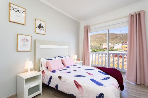 Un dormitorio con una cama y una ventana grande. en Home2Book Charming Apt Mountain Views Los Silos, en Los Silos