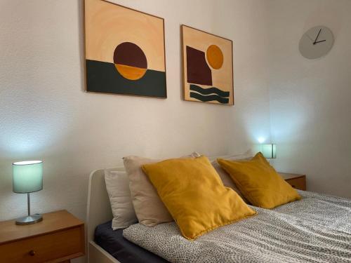 Un dormitorio con una cama con almohadas amarillas y pinturas en Estudio Marina de Santa Pola, en Santa Pola