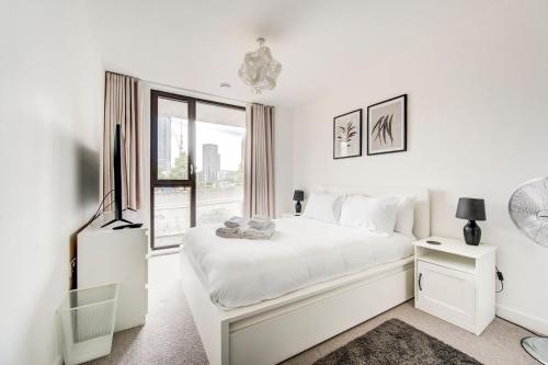 a white bedroom with a white bed and a window at GuestReady - Olympic Park City Living in London