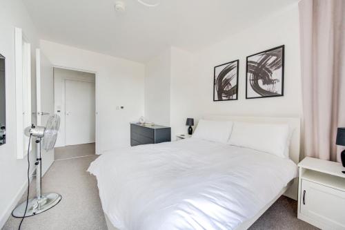 a white bedroom with a white bed and two pictures on the wall at GuestReady - Olympic Park City Living in London