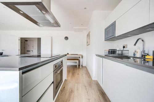 a kitchen with white cabinets and a wooden floor at GuestReady - Olympic Park City Living in London