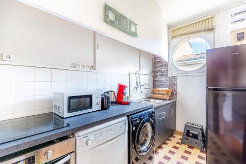 une cuisine avec un micro-ondes et un lave-linge et un sèche-linge dans l'établissement Bel Appartement Capucins - Victoire, à Bordeaux