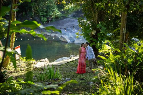 a couple kissing in front of a body of water at El Yunque Glamping River View at Casa Parcha in Naguabo