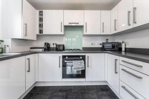 una cocina blanca con armarios y electrodomésticos blancos en GuestReady - O Beehive em Edimburgo, en Edimburgo