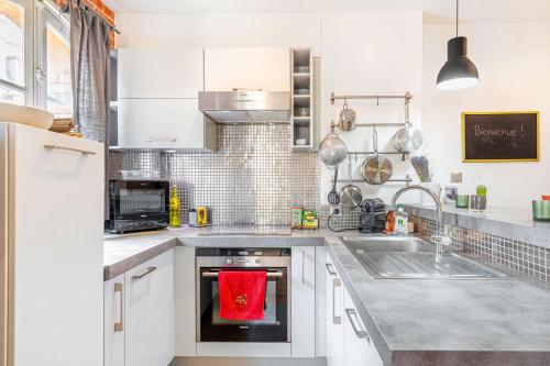 - une cuisine avec des placards blancs et une serviette rouge sur le four dans l'établissement GuestReady - Stay in the heart of Paris, à Paris