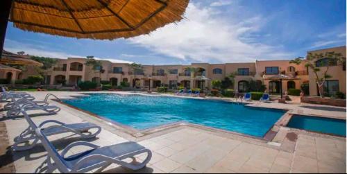 a large swimming pool with chairs and an umbrella at Prime Home The View Hurghada in Hurghada