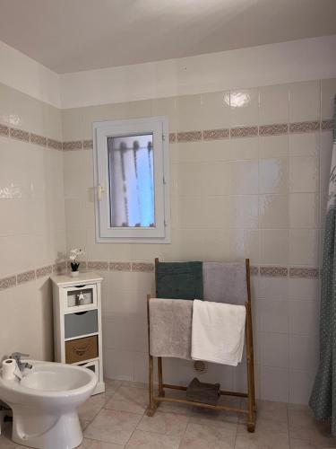 La salle de bains blanche est pourvue d'un lavabo et de toilettes. dans l'établissement Appartement rez de villa, à LʼÎle-Rousse