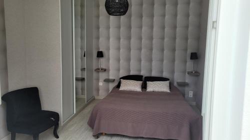 a bedroom with a large bed and a black chair at '' FLEUR DE SEL '' in Saint-Hilaire-de-Riez