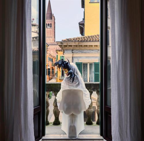 une personne debout devant une fenêtre avec des toilettes dans l'établissement Billie's Flat WHITE - art & design apt in Verona historic centre, à Vérone