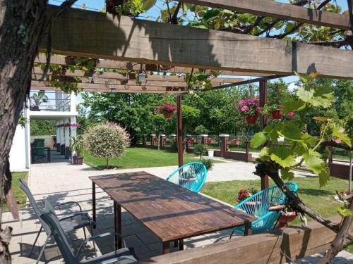 a picnic table and chairs under a wooden pergola at Vila Oaza mira in Vražići