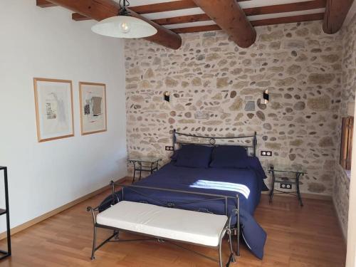 une chambre avec un lit et un mur en pierre dans l'établissement Le Mas de l Olivier, à Saint-Geniès-de-Comolas