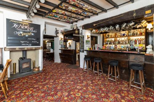 a bar with a fireplace and bar stools at New Inn in Crediton