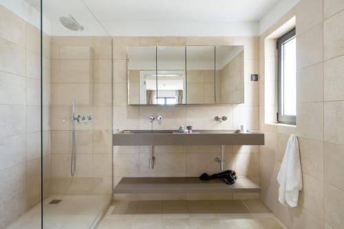 uma casa de banho com um lavatório e um chuveiro com um espelho. em Carvoeiro Gardens em Carvoeiro