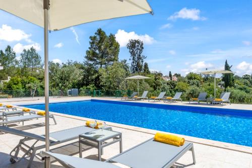a swimming pool with chairs and umbrellas next to it at Carvoeiro Gardens in Carvoeiro