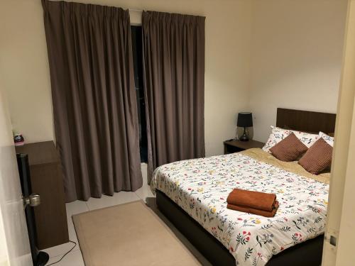 Studio Homestay SGarden Resort Residences في كُوانتان: غرفة نوم مع سرير مع حقيبة بنية اللون