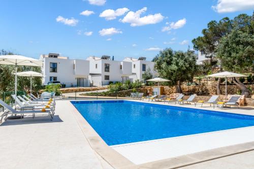 a pool at a hotel with chairs and umbrellas at Carvoeiro Gardens in Carvoeiro