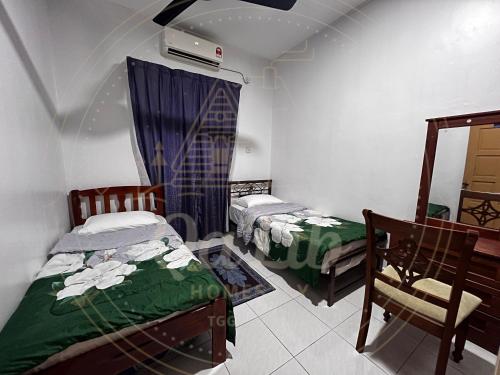 een kamer met 2 bedden en een stoel. bij QALIB HOMESTAY in Kuala Terengganu