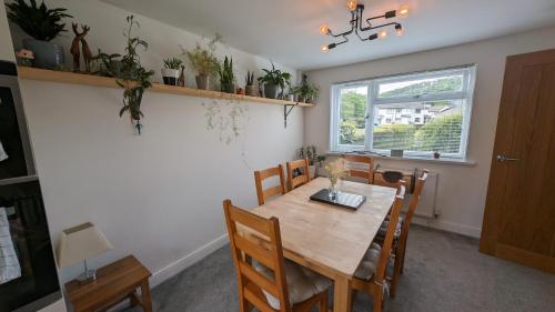 a dining room with a wooden table and chairs at Chy Lowen Private rooms with kitchen, dining room and garden access close to Eden Project & beaches in Saint Blazey