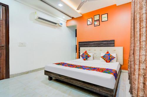 a bedroom with a bed with an orange wall at FabHotel Season Grand in New Delhi