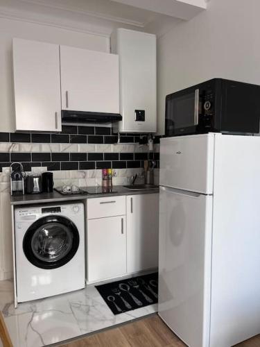 une cuisine avec un réfrigérateur et une machine à laver dans l'établissement Appartement T2 aux portes de Paris, à Asnières-sur-Seine