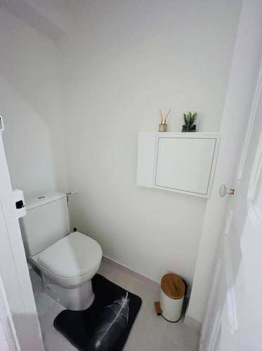 - une salle de bains blanche pourvue de toilettes et d'un tapis noir dans l'établissement Appartement T2 aux portes de Paris, à Asnières-sur-Seine