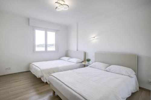 Ce lit se trouve dans un dortoir doté de murs blancs et d'une fenêtre. dans l'établissement Stunning Waterfront Apartment, à Villefranche-sur-Mer