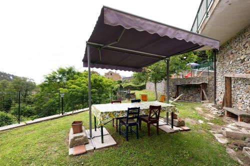 a table and chairs under an umbrella in a yard at Elena e Joerg 1 in Vezzi Portio