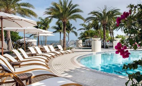 a row of chairs and a swimming pool with palm trees at Endless Summer 42 in Key Largo
