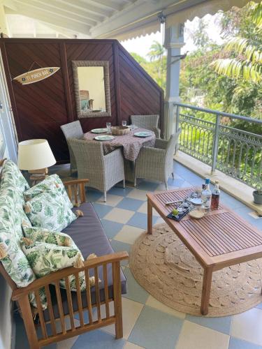 a porch with a couch and a table on a balcony at La Valentine Résidence La Plantation Sainte Marthe in Saint-François