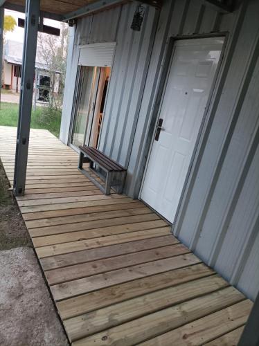 Un porche de madera con una puerta y un banco. en VI-BE-MA, en San Gregorio de Polanco