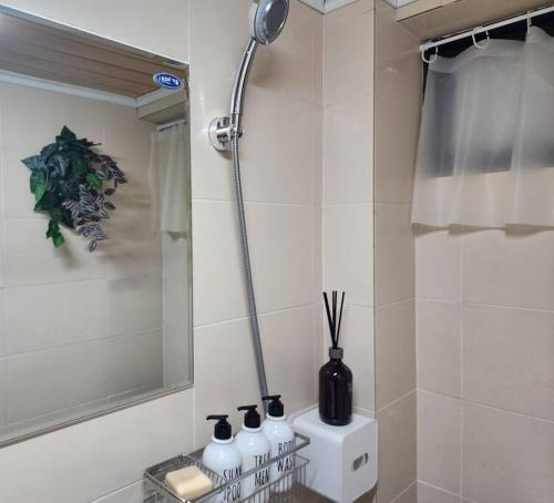 a bathroom with a shower with bottles on a shelf at Green Home Stay in Seoul