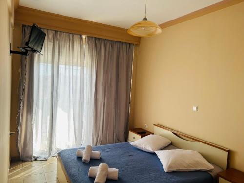 a bedroom with two towels on a bed with a window at Apartments Spartacus in Polychrono